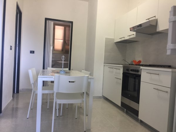 Cucina moderna con tavolo bianco, sedie e mobili bianchi.