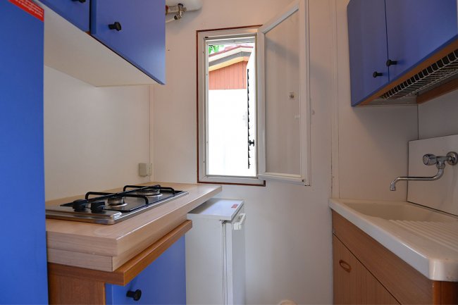 Piccola cucina con piano cottura e pensili blu.