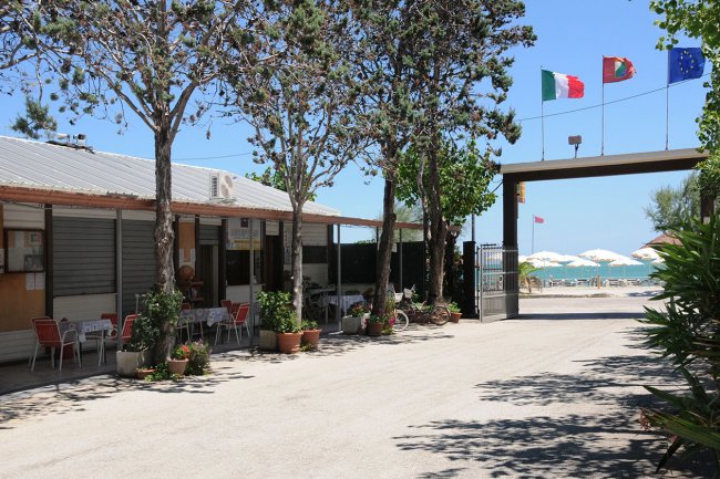 Struttura turistica con bandiere italiane, portoghesi ed europee, vista mare.