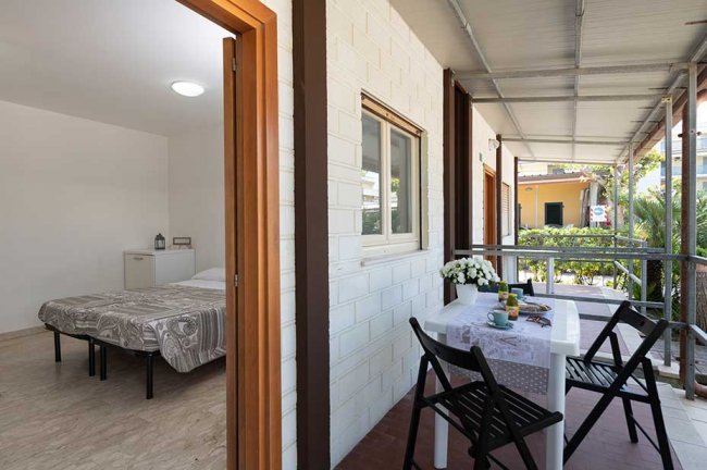 Camera con letto e portico con tavolo e sedie.