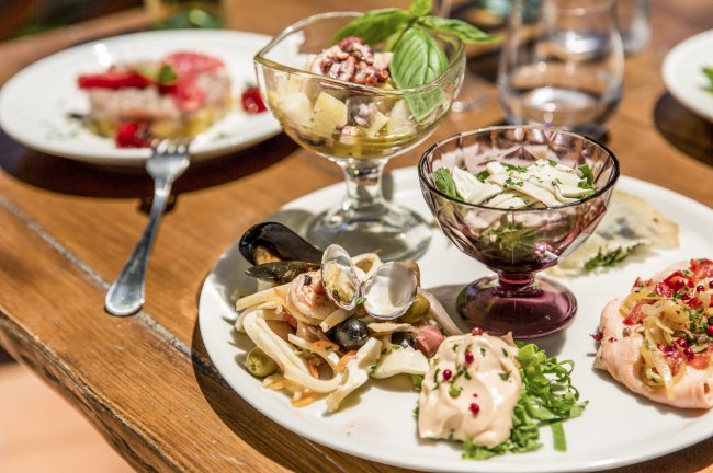 Un piatto di antipasti assortiti con frutti di mare, insalate e salse.