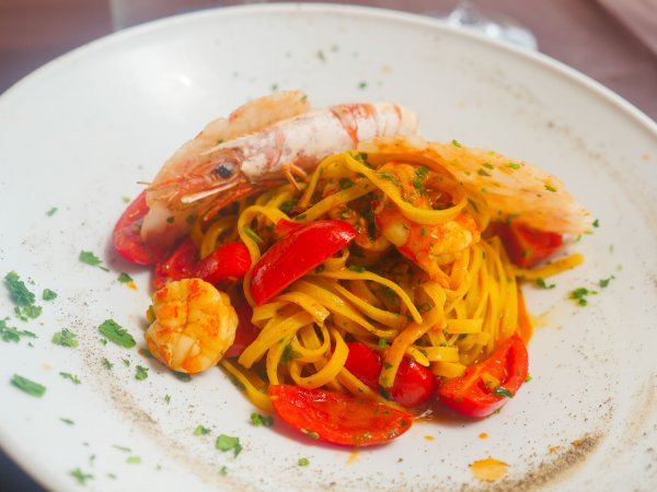 Un piatto di pasta con frutti di mare, pomodori e prezzemolo.