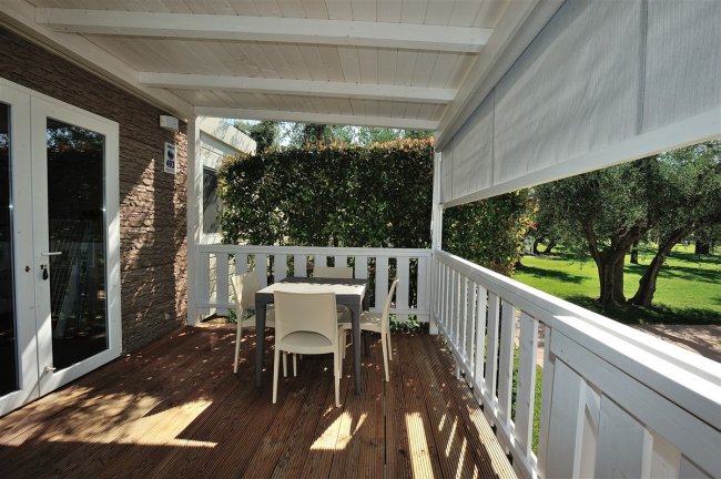 Veranda con tavolo e sedie, vista su giardino.