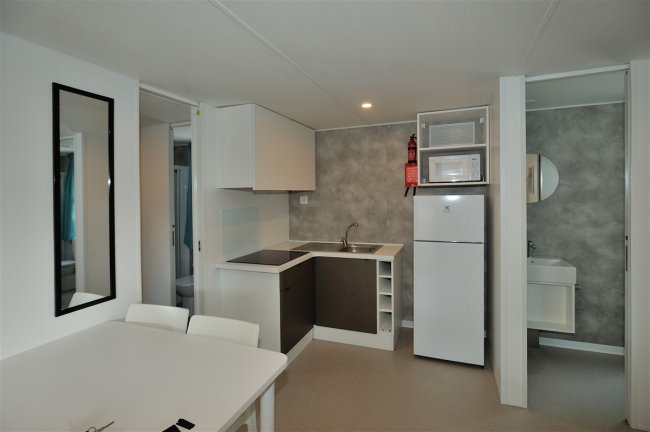 Una cucina moderna con un tavolo bianco, elettrodomestici e lavandino.