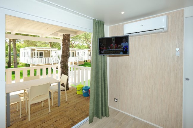 Interno con veranda, tavolo da pranzo, televisione e aria condizionata.