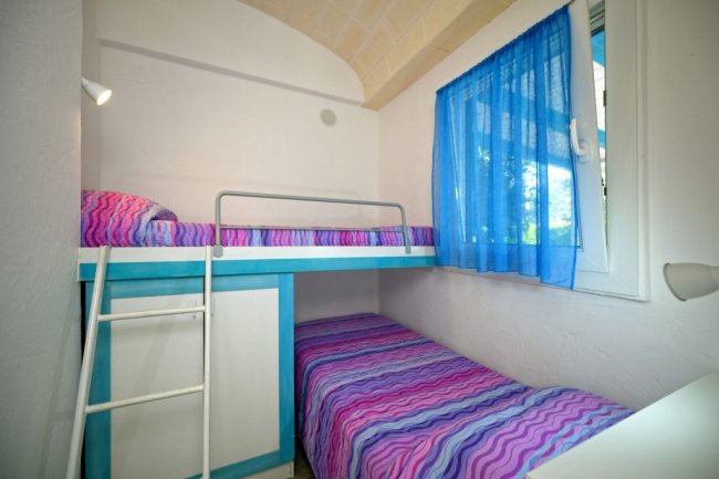 Camera con letto a castello e tende blu, ambiente luminoso.