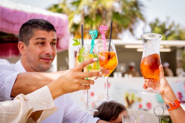 Un brindisi con bicchieri di cocktail variopinti tra quattro persone.
