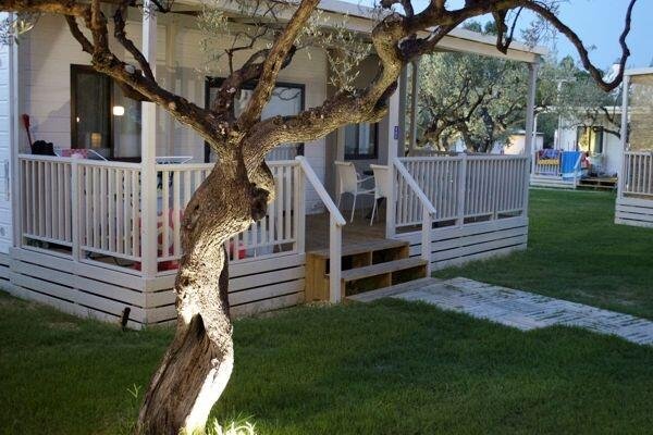 Casetta bianca con veranda e albero nel giardino.