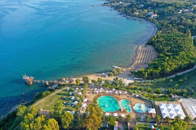 Una spiaggia con ombrelloni e una piscina vicino al mare.