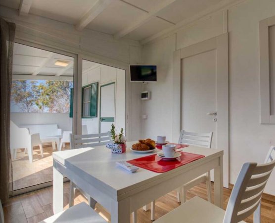 Sala da pranzo bianca con tavolo apparecchiato.