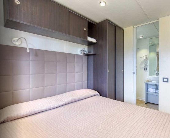 Camera con letto matrimoniale, armadi scuri e bagno in fondo.