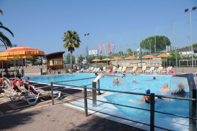 Piscina all'aperto con lettini e ombrelloni gialli e arancioni.