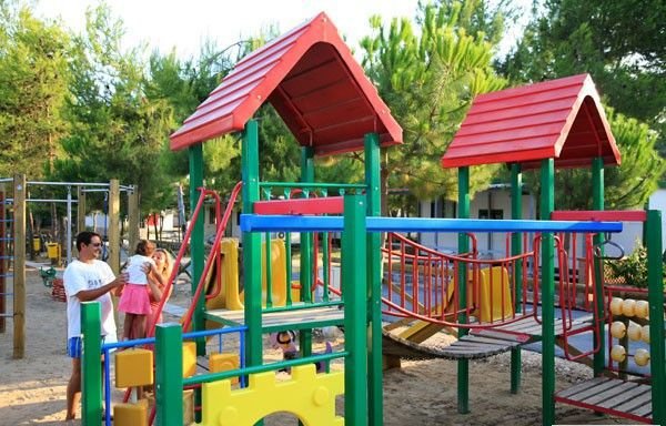 Area giochi all'aperto con strutture colorate per bambini e persone.