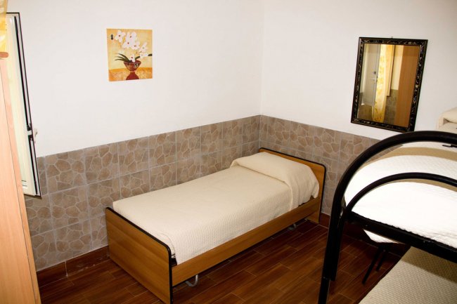 Camera con letto singolo, letto a castello nero, specchio e quadro con fiori.