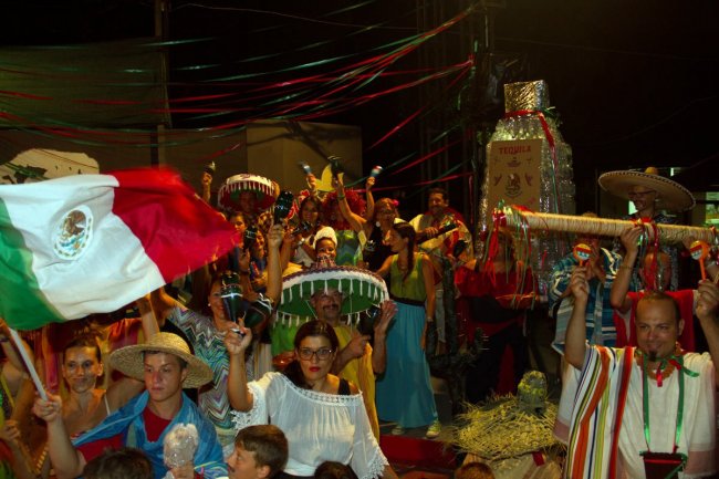 Gruppo di persone in festa, alcune con sombreri e una bandiera messicana.