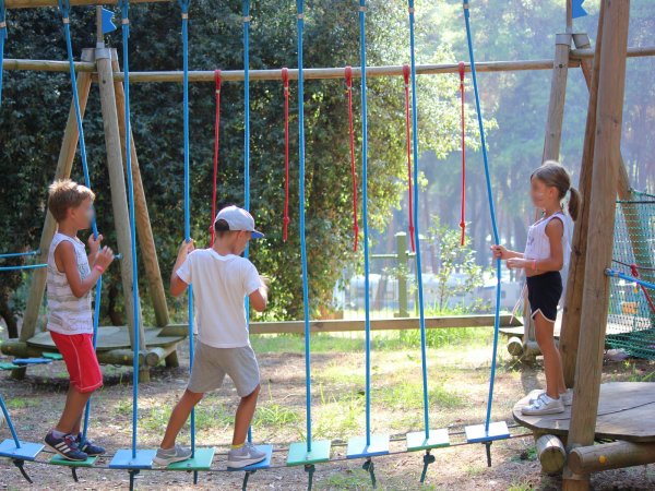 Bambini su un percorso a ostacoli in un parco avventura.