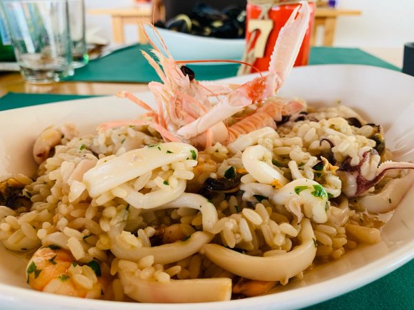 Risotto ai frutti di mare con gamberi e calamari, servito su un piatto bianco.