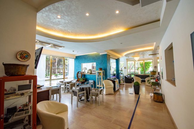 Sala moderna con arredamento chiaro, pareti blu e angolo relax.