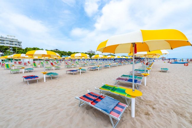 Vista laterale di una spiaggia con ombrelloni gialli e sedie.