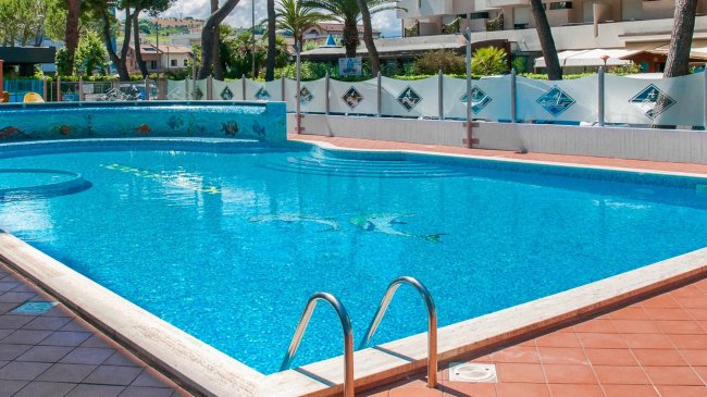 Piscina azzurra all'aperto con piastrelle rosse attorno.
