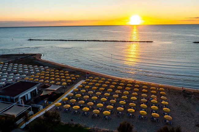 Spiaggia all'alba con ombrelloni gialli.