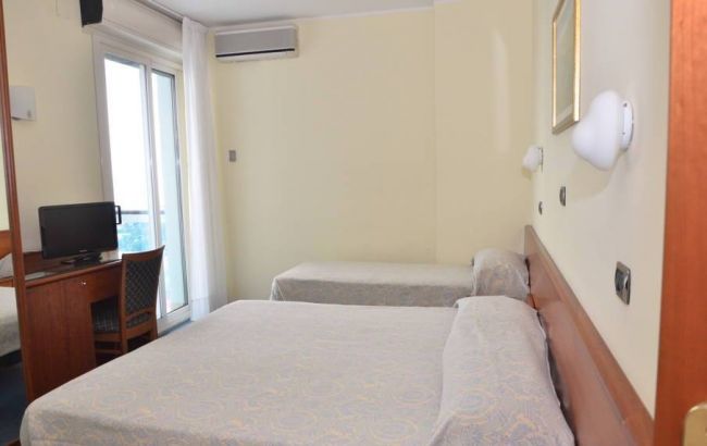 Camera da letto con due letti singoli, scrivania, una TV e aria condizionata.