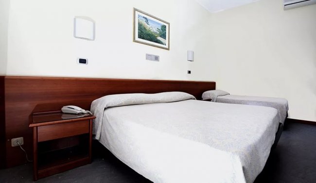 Letto matrimoniale e letto singolo sotto un quadro, telefono sul comodino.