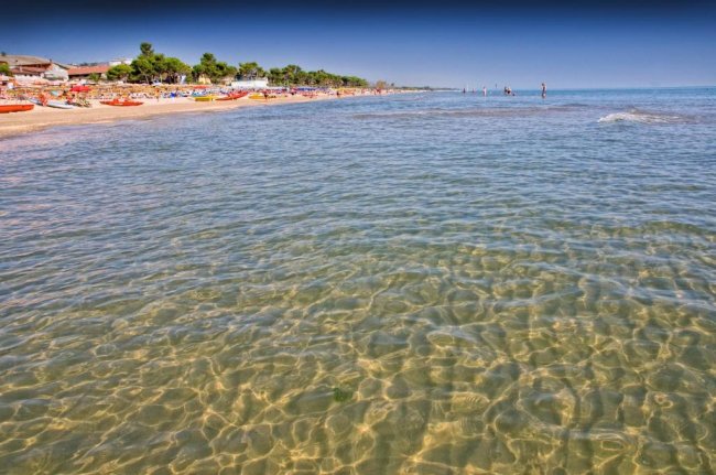 Spiaggia con mare limpido e cielo blu.