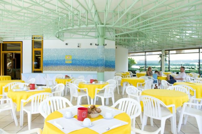 Sala ristorante con tovaglie gialle e sedie bianche.