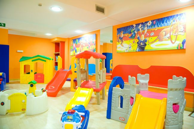 Sala giochi per bambini con scivoli colorati e giocattoli.