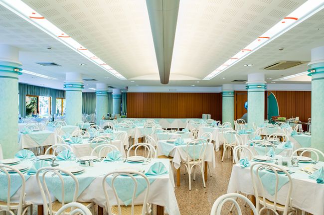 Ampia sala da pranzo con tavoli apparecchiati, ambientazione luminosa.