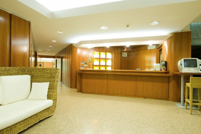 Area reception con divano in rattan e banco in legno.