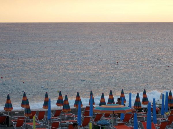 Tramonto su spiaggia con ombrelloni colorati e mare.