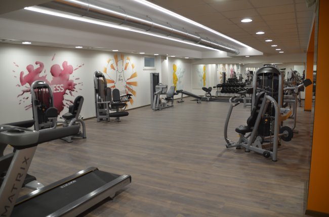 Palestra luminosa con attrezzi per allenamento e decorazioni murali colorate.