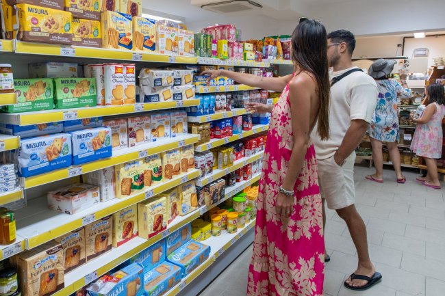 Coppia in un supermercato esamina scaffali pieni di biscotti.