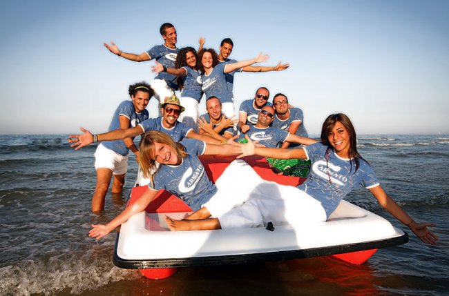 Gruppo di persone sorridenti su un pedalò al mare.