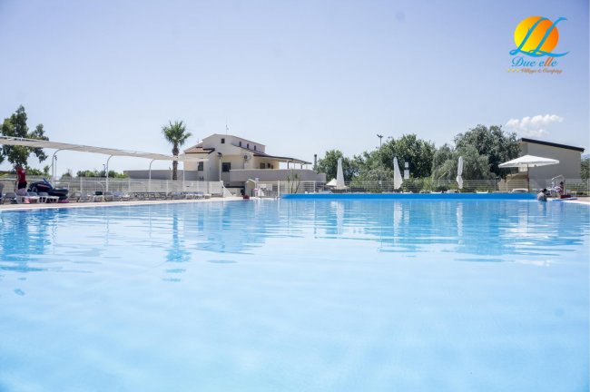 Vista di una grande piscina all'aperto con sedie a sdraio e ombrelloni.