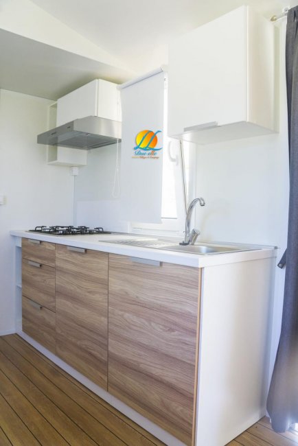 Cucina moderna con piano cottura a gas e lavello, mobili in legno chiaro.