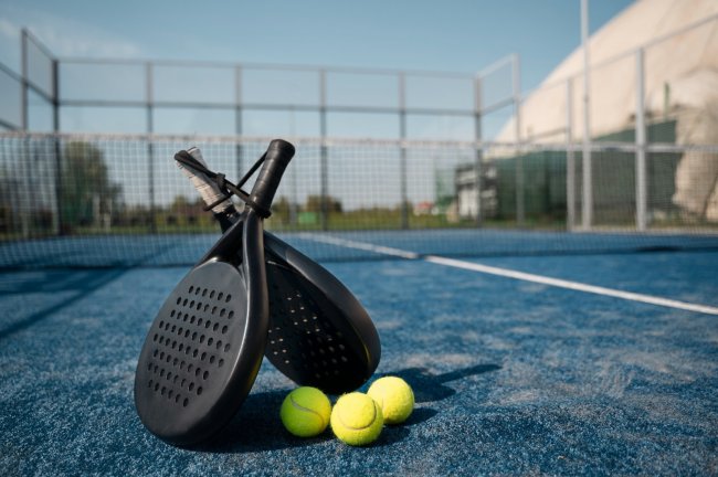 Racchette e palline da padel su campo blu.