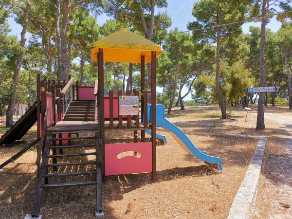 Parco giochi con scivolo e alberi intorno.