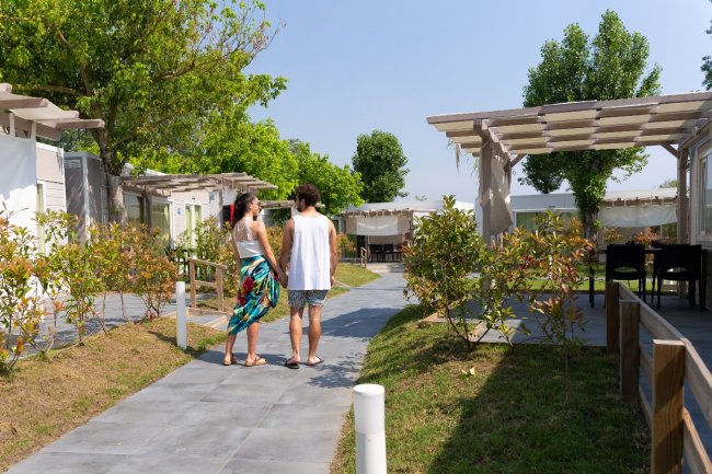 Coppia cammina su un vialetto circondato da giardini e bungalow.