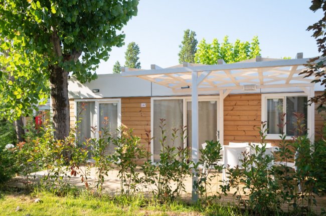 Bungalow in legno con patio e pergolato bianco.