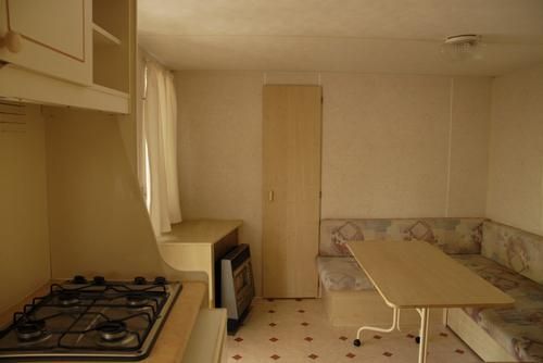 Interno di roulotte con tavola, divano ad angolo e finestra.