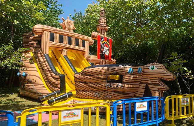 Gonfiabile a forma di nave pirata con scivoli colorati.