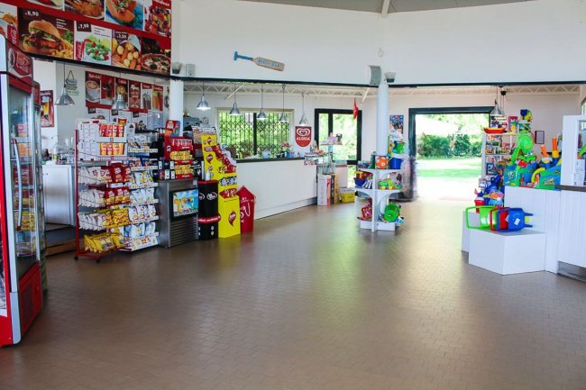 Un minimarket con scaffali pieni di snack, gelati e giocattoli colorati.