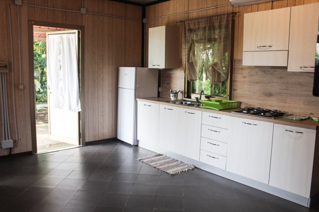 Cucina moderna con pavimento scuro e frigorifero bianco.