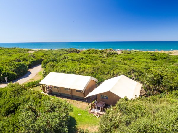 Due tende glamping tra la vegetazione con vista sull'oceano.