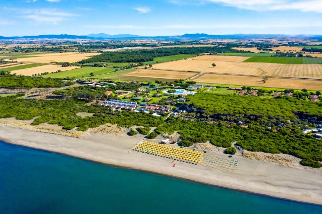 Veduta aerea di una spiaggia, campagne e un resort circondato da alberi.