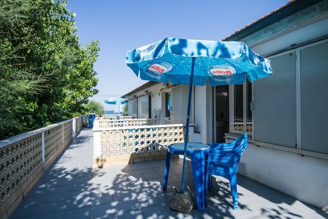 Tavolo blu con ombrellone su terrazza soleggiata.