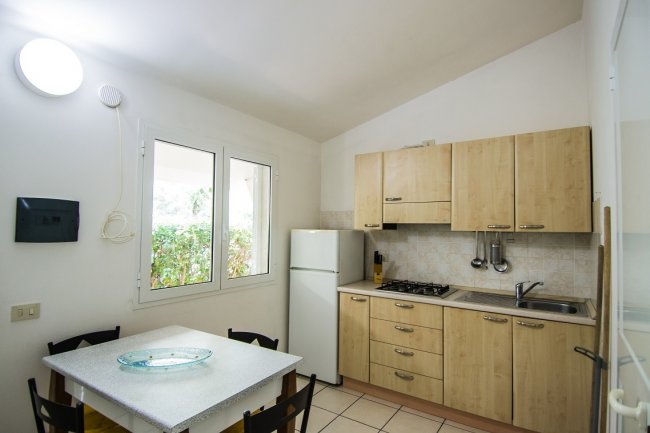 Cucina luminosa con tavolo e frigorifero.